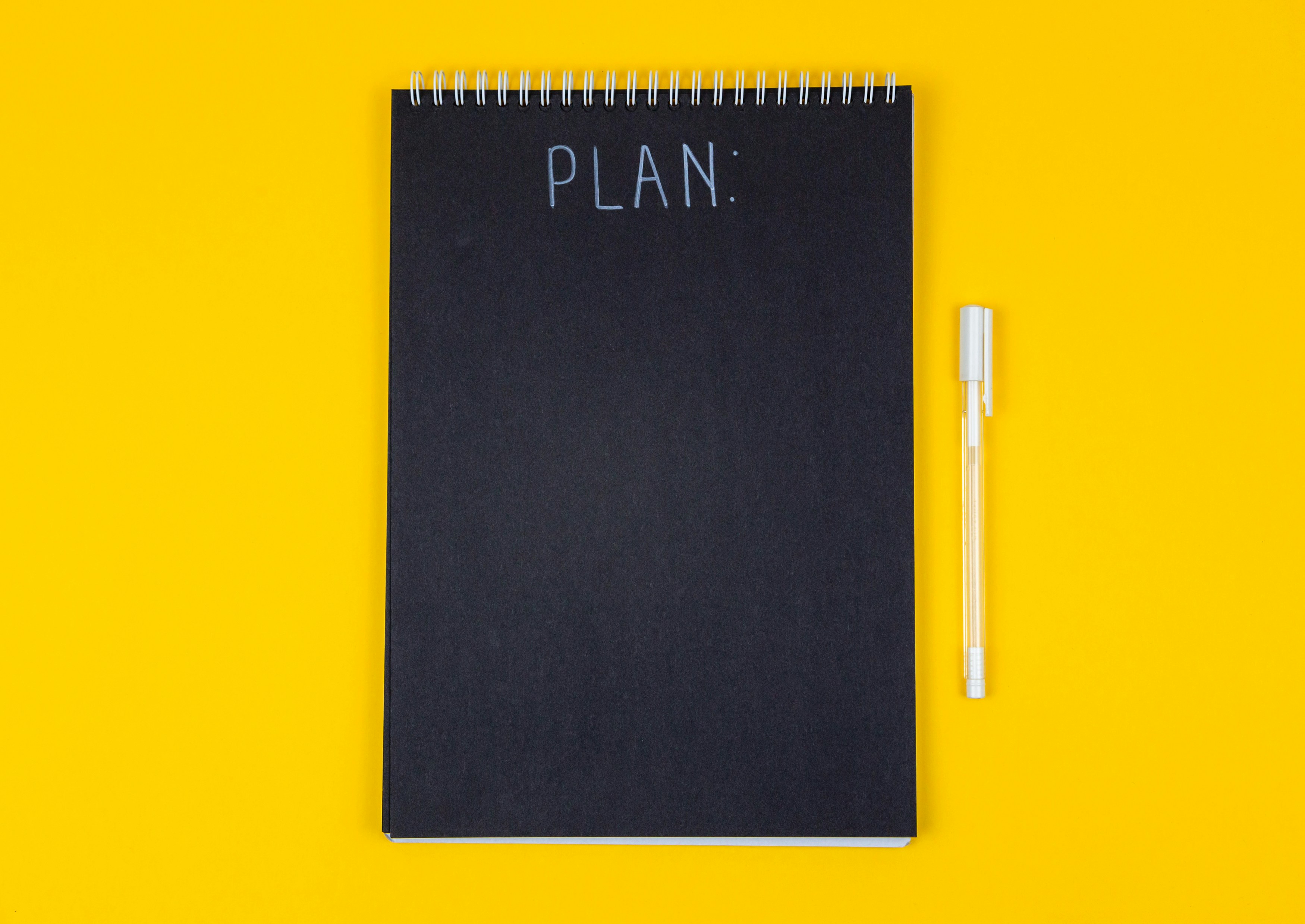 notebook with the word "plan" on it and a pen